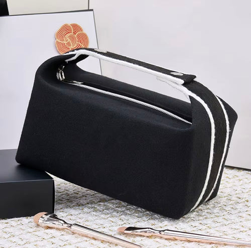 Svart Alanya Makeup Bag i canvas med vita detaljer, dragkedja och öppningsbart bärhandtag från Natta Collection.