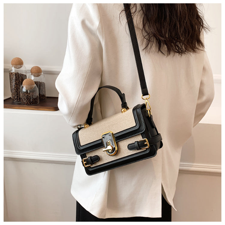 Handväska beige och svart buren som crossbody med justerbar axelrem och elegant design.