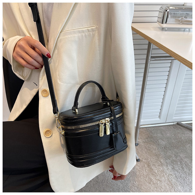 Handväska svart buren som crossbody med justerbar axelrem och kompakt design.