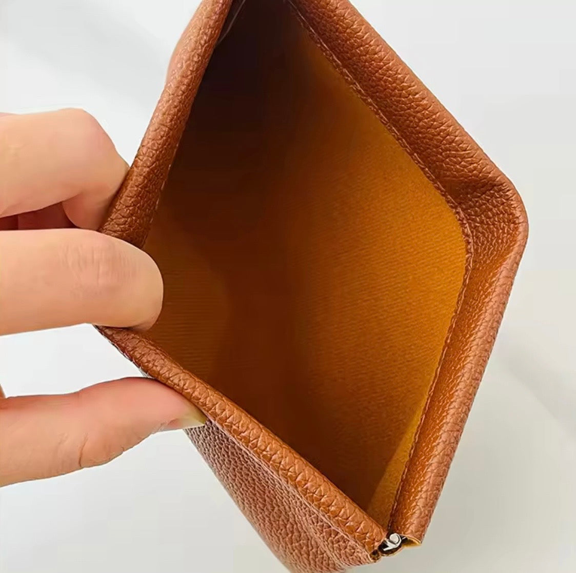 Beige förvaring i större storlek med metallspänne som öppnas med ett enkelt tryck för smycken, hörlurar, mynt och andra små tillhörigheter.