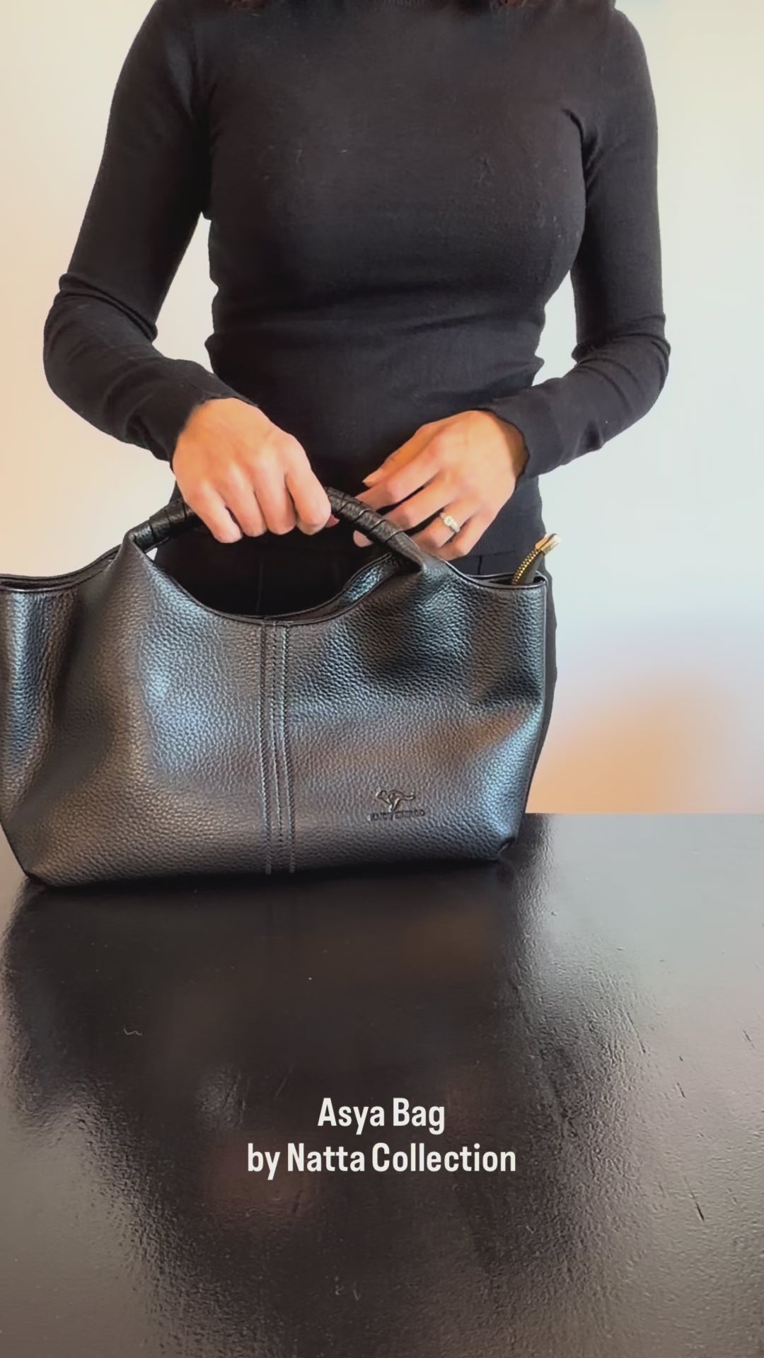 Produktvideo som visar Asya Bag, en svart handväska med handtag, strukturerad yta och rymlig design, från olika vinklar och i närbild.