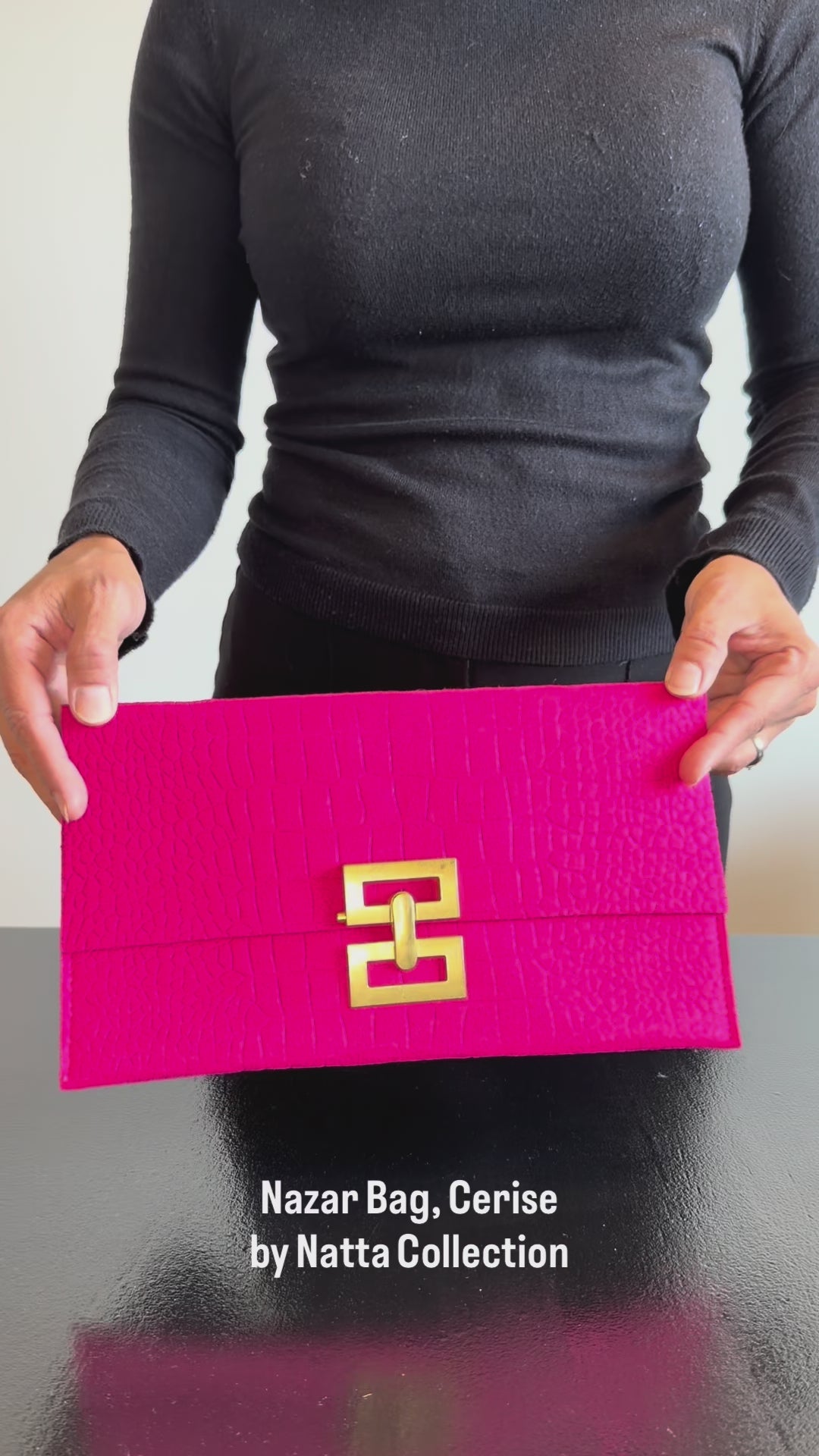 Produktvideo som visar Nazar Bag i cerise från olika vinklar samt kuvertväskans struktur, guldfärgade spänne och detaljer.