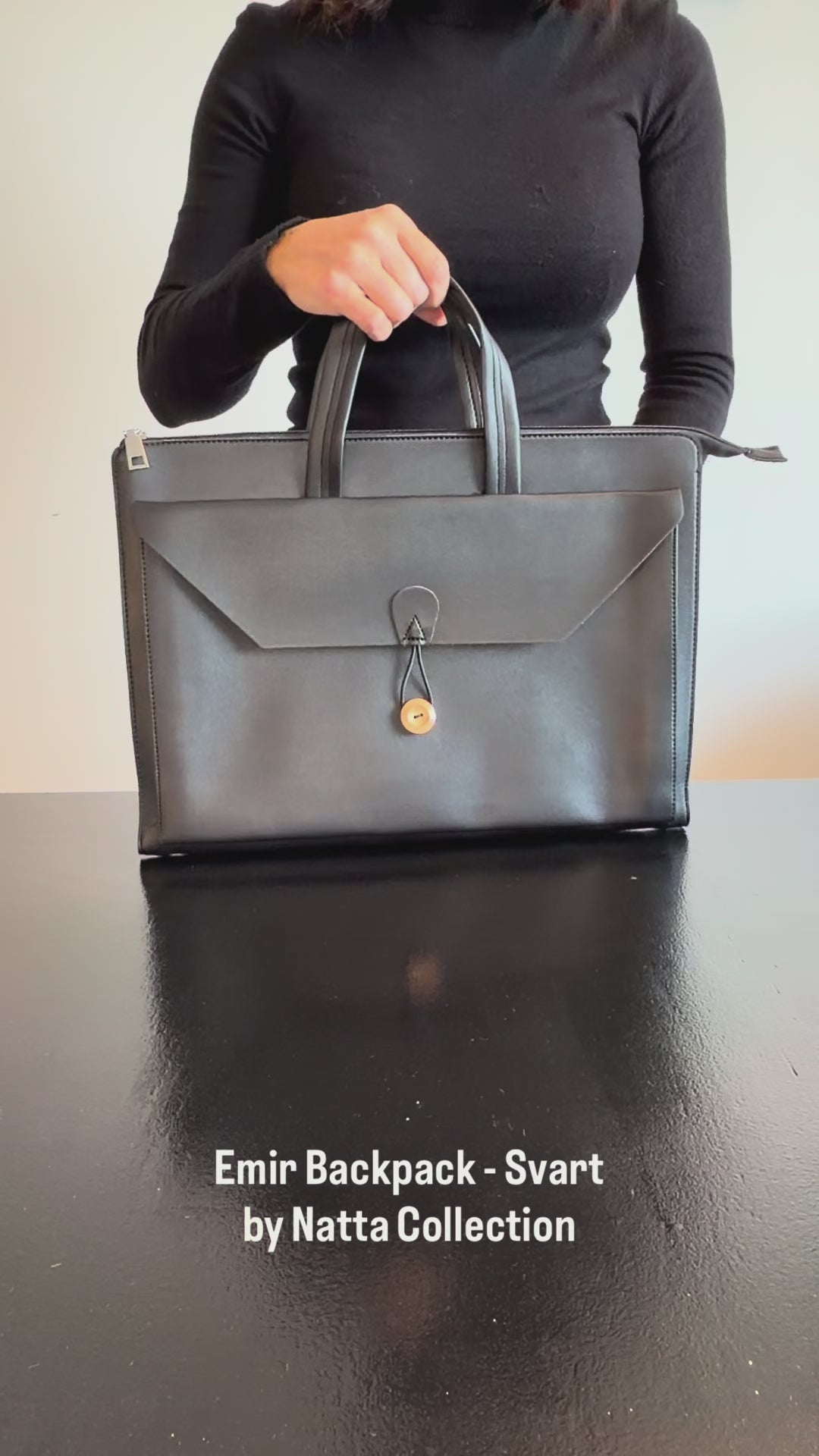 Produktvideo som visar Emir Laptop Bag, en svart datorväska med handtag, axelrem och lock med dekorativ stängning, från olika vinklar och i närbild.